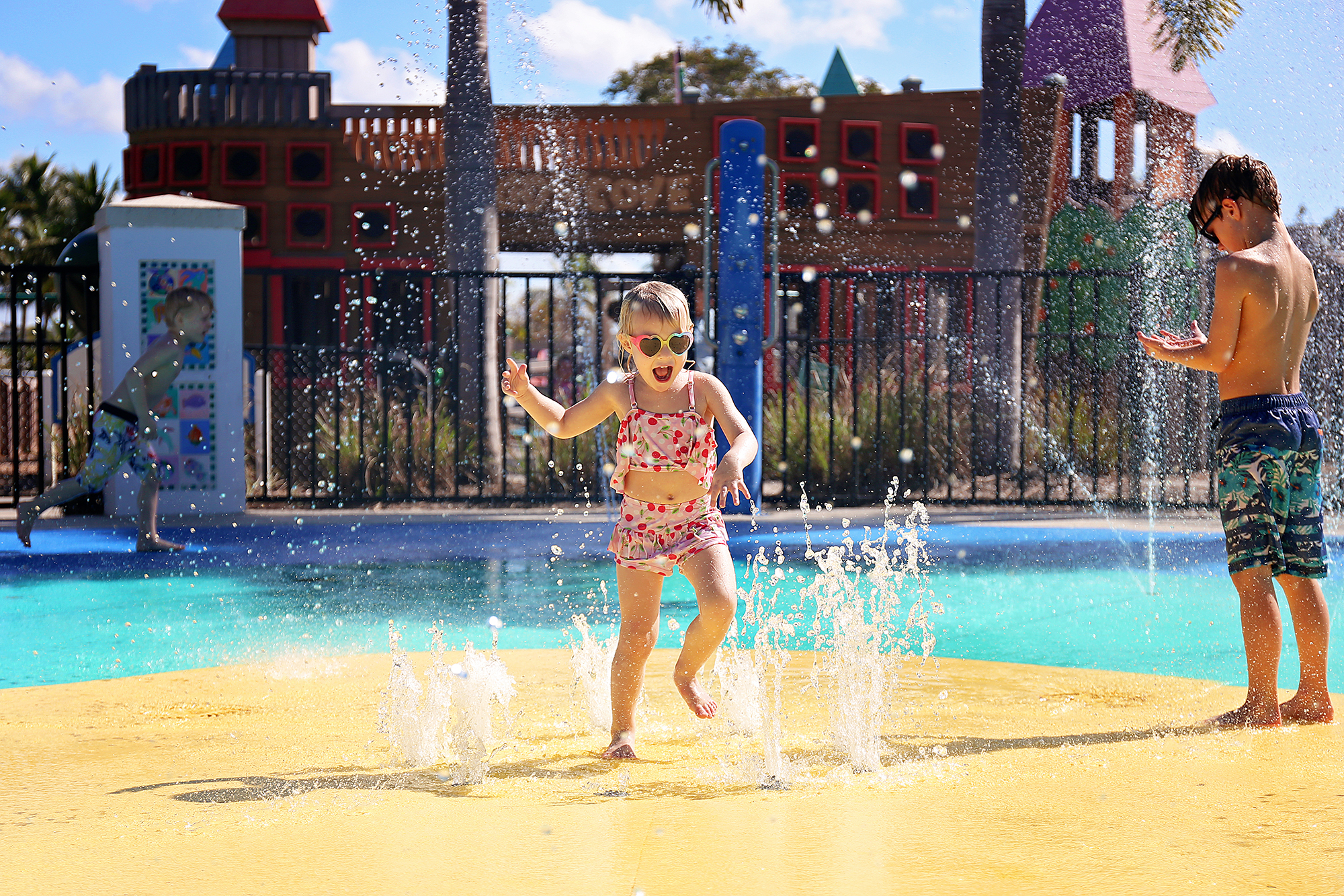 Happy Toddler Child Jumping and Playing in Water Fountains at Splash Park